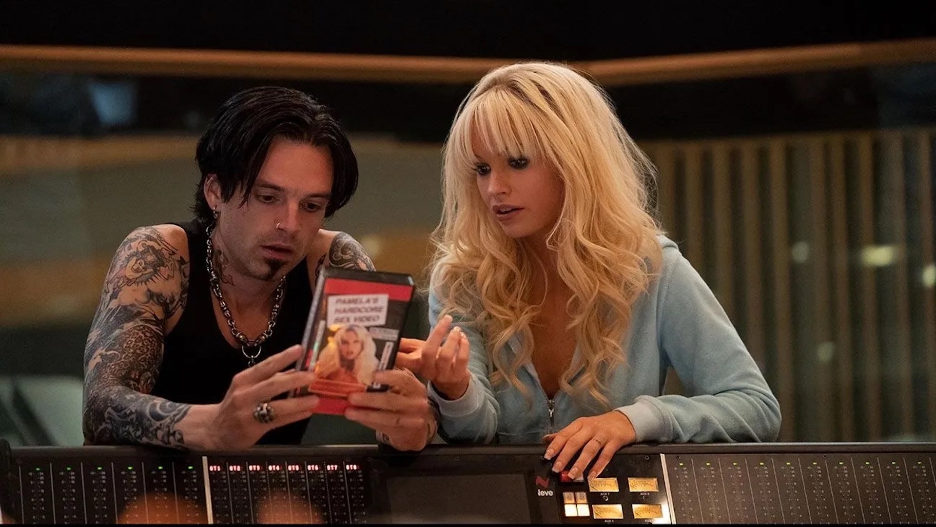 Pamela Anderson (Lily James) and Tommy Lee (Sebastian Stan) looking at a VHS in a music studio in 'Pam & Tommy,' 5 Ways To Write a Modern Biopic