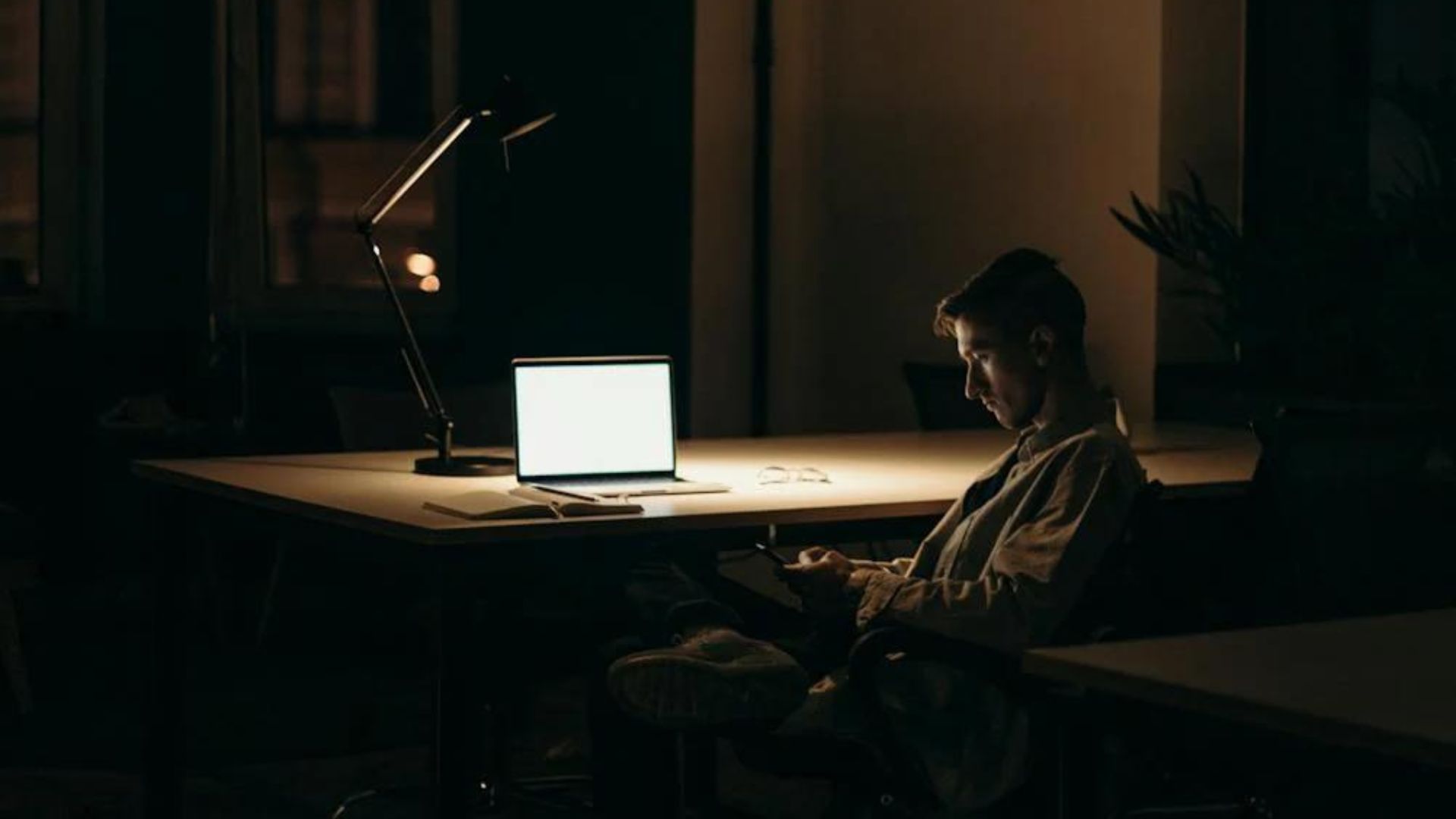 Man texting on his phone in front of a laptop, Crafting the Big Picture with Final Draft 13's Powerful New Tool